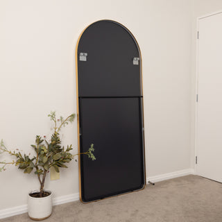 Rear view of the Aurelia arched full-length mirror showing the sturdy black back panel, gold frame edges, and secure wall-mounting brackets.