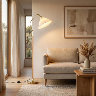 Aurelia Pleated Fabric Floor Lamp glowing warm beside a sofa in a New Zealand living room at night