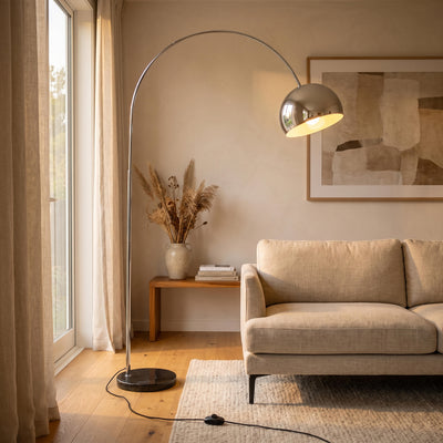 Cosmo Chrome Marble Base Floor Lamp glowing warm beside a sofa in a New Zealand living room at night