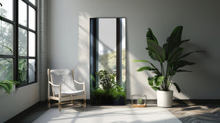 Facet straight-edged full-length freestanding mirror in black with a sleek 170x70 cm design, placed in a minimalistic room setting with plants