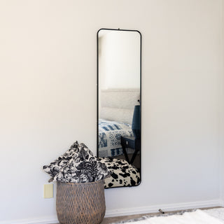 The Lithe X Full-Length Mirror (155x45cm) elegantly wall-mounted in a modern bedroom setting. This wall mirror features a slim black metal frame and a sleek, minimalist design. Perfect for small spaces, it provides a clear and full reflection while enhancing home décor. The mirror is securely mounted on the wall, offering both functionality and style. | C&F Creation