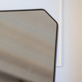 Close-up of the angled top corner of the Prism Octagonal mirror, showing smooth finishing and slim black frame. Modern geometric edge design from C&F Creation.