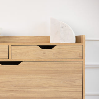 Close-up of the Risa Slim Shoe Cabinet’s upper section in oak finish, showing two top drawers with cut-out handles. A white marble bookend rests on top, highlighting the cabinet’s clean, modern design and versatile storage style.