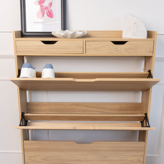 Front view of the Risa Slim Shoe Cabinet in oak finish, shown with two top drawers and three open tilt-down compartments. One compartment displays a pair of shoes neatly stored, highlighting the cabinet’s slim, practical storage design for narrow spaces.