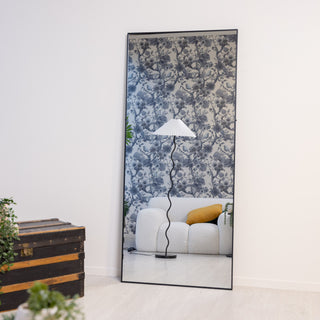 Front-facing image of the Zenith X full-length mirror 180x80cm, with a bold black frame and crisp reflection, styled with green foliage and neutral tones.
