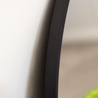 A close-up view of the Zia Round Wall Mirror’s matte black aluminium alloy frame, highlighting its sleek, modern design and high-quality finish. The minimalist frame blends effortlessly with contemporary interiors, making it a stylish addition to any space. | C&F Creation