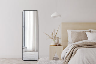 Lithe Rounded Corner full-length freestanding mirror with black frame in a minimalist living room setup.