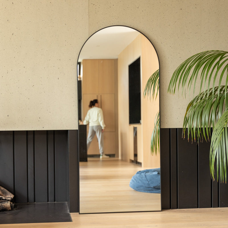 A freestanding full length arched mirror leaning against a wall in a styled New Zealand bedroom