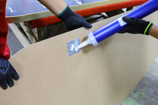 Worker applying adhesive to the back of a C&F Creation full-length mirror, ensuring secure and precise attachment of components for enhanced durability and stability.