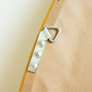Close-up of the Aure Round Wall Mirror’s back metal hook and screws showing the secure mounting design and smooth beige frame edge.