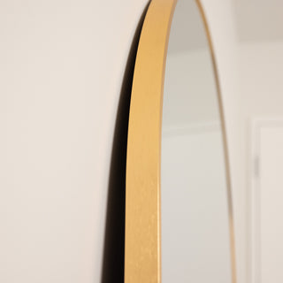 Side close-up of the Aurelia arched full-length mirror, highlighting the slim gold aluminium frame and smooth finish against a white wall.
