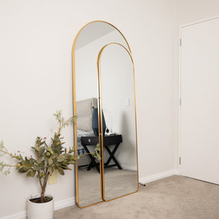 Aurelia arched full-length mirror set with slim gold frames, shown from a slight side angle in a modern bedroom, featuring both 180x80cm and 160x50cm sizes together.