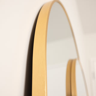 Close-up of the Aurelia arched full-length mirror set, highlighting the slim gold aluminium frame and smooth curved edge.