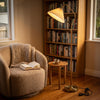 Aurelia Pleated Fabric Floor Lamp arched over an armchair, lighting a quiet reading corner