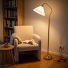 Aurelia Pleated Fabric Floor Lamp arched over an armchair, lighting a quiet reading corner