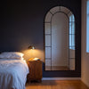 Bastia X black arched window full length mirror 200 x 100cm in a bedroom at dusk beside a brass lamp