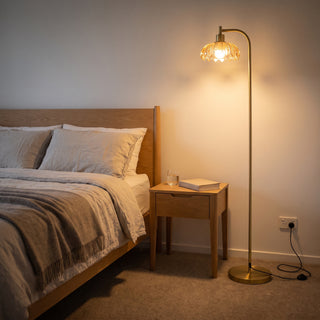Camille Amber Petal Glass Floor Lamp casting a soft warm glow beside the bed in a cosy bedroom