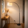 Flore Black Arc Floor Lamp hanging its linen drum over a console in a stylish hallway entry