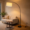 Flore Black Arc Floor Lamp glowing warm beside a sofa in a New Zealand living room