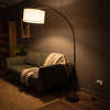 Flore Black Arc Floor Lamp glowing warm at night as the only light in a dark living room