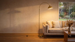New floor lamp range hero, Orsay gold arc floor lamp glowing warm over a sofa in a New Zealand living room