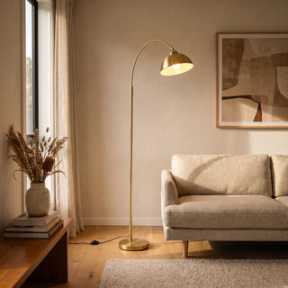 Orsay Gold Arc Floor Lamp glowing warm beside a sofa in a New Zealand living room at night