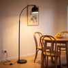 Saturne Black Globe Arc Floor Lamp beside a round oak dining table in the evening