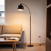 Saturne Black Globe Arc Floor Lamp glowing warm beside a sofa in a New Zealand living room