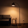 Saturne Black Globe Arc Floor Lamp glowing warm at night as the only light in a dark living room