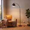 Saturne Black Globe Arc Floor Lamp lighting a reading corner beside a leather armchair