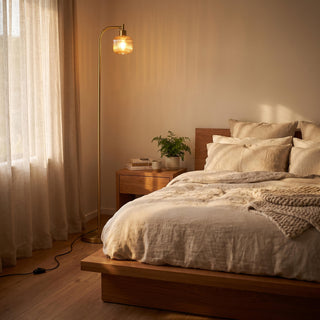 Solara Fluted Lantern Floor Lamp casting a soft amber glow beside the bed in a cosy bedroom