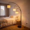 Trilogy 3-Light Floor Lamp casting a soft glow beside a bed in a calm bedroom