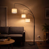 Trilogy 3-Light Floor Lamp glowing warm at night as the only light in a dark living room