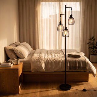Voltaire 3-Light Cage Floor Lamp casting a soft warm glow beside the bed in a cosy New Zealand bedroom