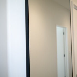A close-up of the wall-mounted Facet full-length mirror, showcasing its premium frame and installation.