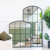 Le Vue and Le Beau window arched mirror set featuring two black metal framed arched mirrors in 190x90cm and 120x100cm, styled leaning against a wall in a bright New Zealand living room, reflecting natural light, greenery, and modern interior decor.