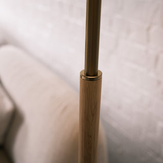 Close up of the Luma Pleated Floor Lamp showing the brushed brass connector and natural wood pole, highlighting the smooth transition between the materials.