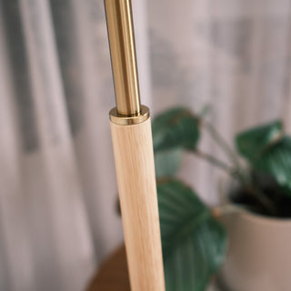 Close up of the Luma Pleated Floor Lamp showing the brushed brass connector and natural wood pole, highlighting the warm, refined material combination.