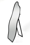 Angled view of Nova Irregular Full-Length Mirror with a sleek black frame and artistic curved design