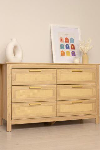 Close-up of the Raya 6-drawer lowboy showing natural oak frame, rattan drawer panels and gold handles.