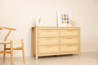 Rattan-front oak 6-drawer lowboy styled in a simple setting with a wooden chair and neutral decor, showing the dresser in a minimal interior.
