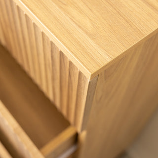 Close-up detail of the Reede Tallboy 5-Drawer showing the smooth oak finish top panel and vertical fluted drawer front design, highlighting craftsmanship and modern texture.