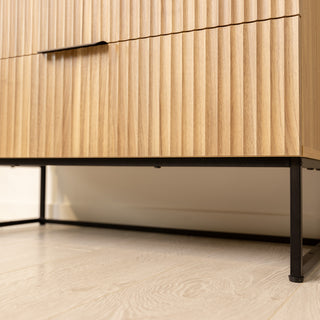 Close-up of the Reede Tallboy 5-Drawer showing the fluted oak drawer fronts and strong black metal legs, designed for stability and a modern look.