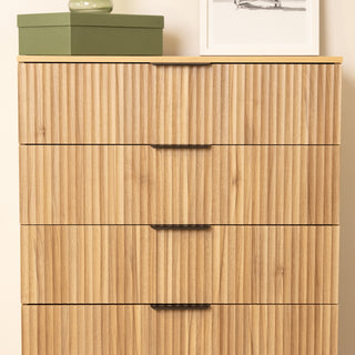 Close-up front view of the Reede Tallboy 5-Drawer dresser, showing the vertical fluted drawer fronts, oak wood finish, and slim black handles for a modern minimalist look.