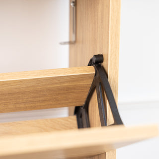 Close-up detail of the Risa Slim Shoe Cabinet showing the sturdy black support bracket and wooden tilt-down mechanism, designed for secure and smooth shoe storage in a slim oak finish cabinet.