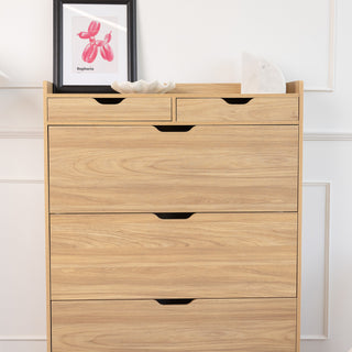Front view of the Risa Slim Shoe Cabinet in a warm oak finish, featuring two top drawers and three spacious shoe compartments with cut-out handles, styled with framed artwork, a decorative bowl, and marble accent on top.