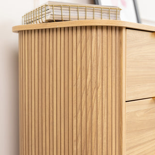 Close-up of the Ruelle 6 Drawer dresser’s side panel, featuring a vertical fluted design in a warm oak finish. The detailing adds texture and elegance, complementing the dresser’s modern silhouette.