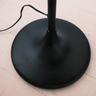 Close up of the Slate Tray Floor Lamp’s round matte black metal base with power cord visible, showing the smooth finish and sturdy structure on a light timber floor.