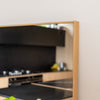 Close-up of the Solene X full-length mirror showing the 45 mm wooden PS frame with smooth edges and a natural oak texture. The 4 mm double silver glass reflects a modern kitchen interior with black cabinetry and light wood finishes, highlighting the mirror’s clarity and fine craftsmanship.