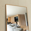Corner detail of the Solene X full-length mirror, showing its light wooden PS frame and 4 mm double silver glass. The mirror reflects a bright, modern living room with soft toned furniture and oak cabinetry, illustrating how the 170 x 70 cm mirror can blend seamlessly into New Zealand homes with warm, natural interiors.